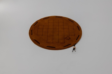 Fox and geese board game on a round dark brown leather playing field
